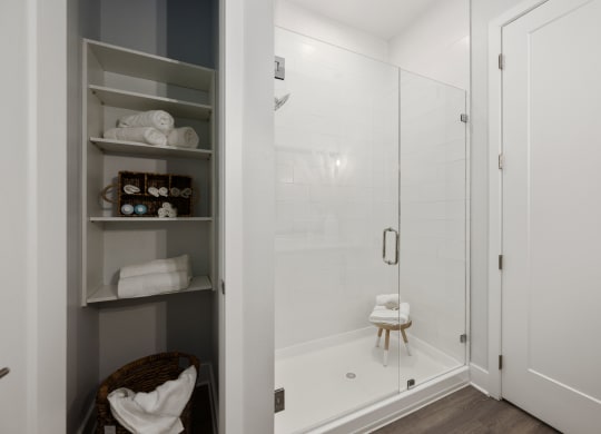 a white bathroom with a shower and shelves in it