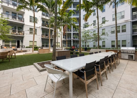 a long communal table and chairs in an apartment courtyard