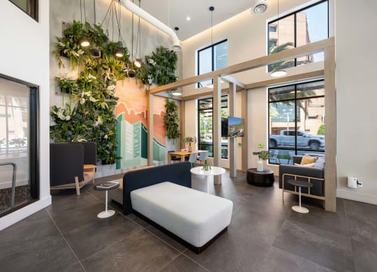 a lobby with couches and chairs and a wall of plants