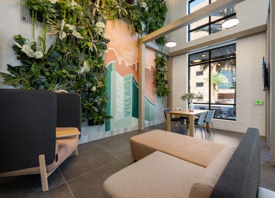 a living room with couches and a table and a wall of plants