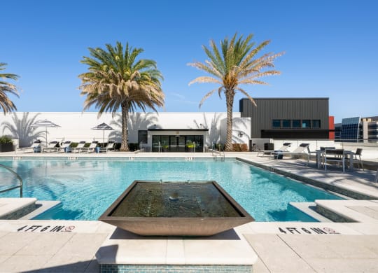 a swimming pool with palm trees and a building in the background