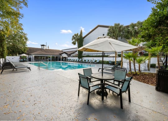 a swimming pool with a patio with chairs and an umbrella