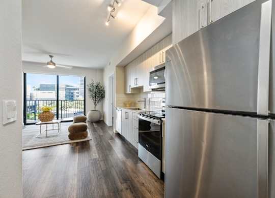 A modern kitchen with a stainless steel refrigerator and wooden flooring.