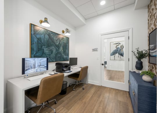 a community office with two computers and a painting on the wall