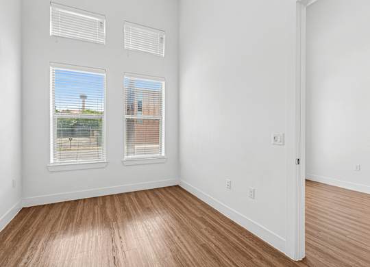 A room with two windows and wooden floors.