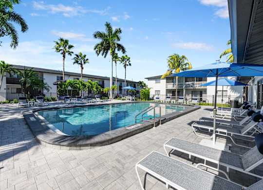 a swimming pool with chairs and umbrellas in front of a building