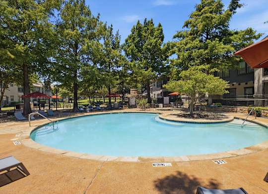 A small pool surrounded by trees and a building.