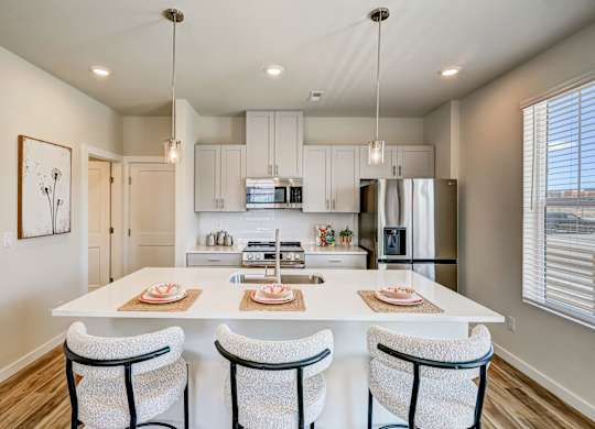 A modern kitchen with a large island and chairs.