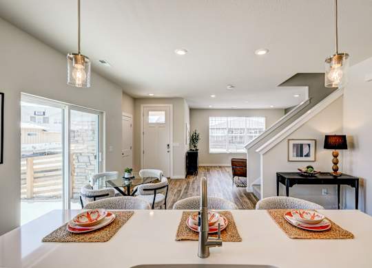 A modern dining room with a long table set for a meal.