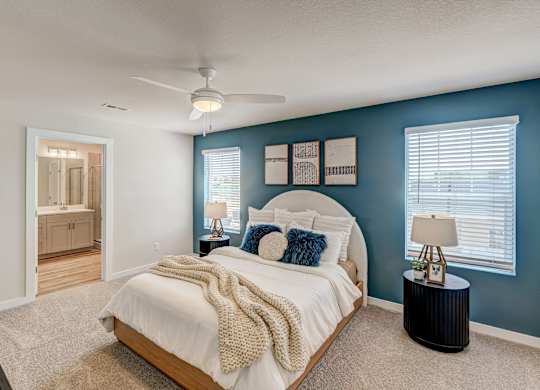 A bedroom with a bed, nightstand, and a plant.