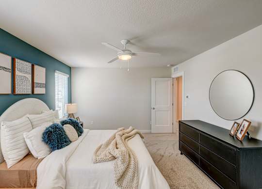 A bedroom with a bed, dresser, and mirror.