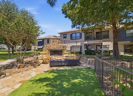 A modern house with a stone fireplace in the backyard.