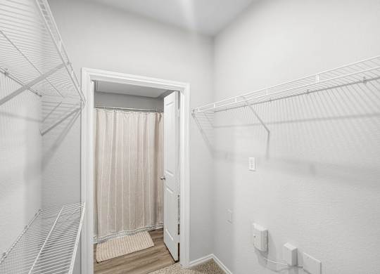 A white closet with a doorway leading to a bathroom.