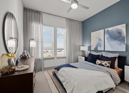 A bedroom with a large bed, a dresser, and a ceiling fan.