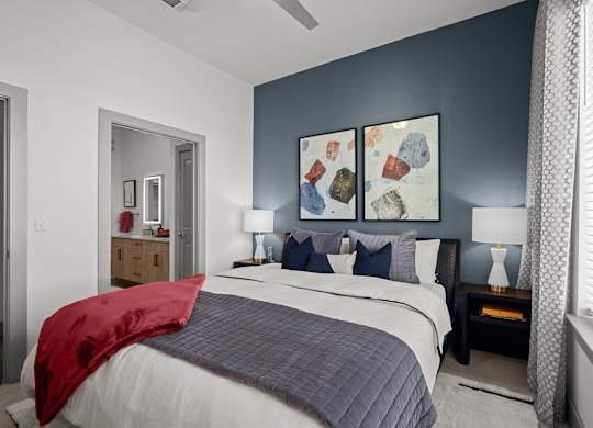 A bedroom with a bed, nightstands, and a painting on the wall.