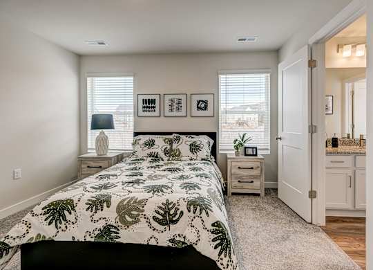 A bedroom with a large bed and a window with blinds.