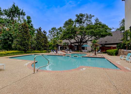 a swimming pool with trees and a building in the background