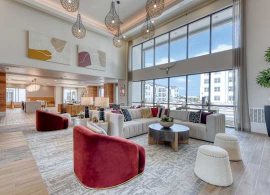 a living room with couches and chairs and large windows