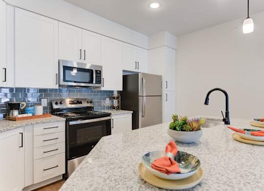 a kitchen with white cabinets and black appliances and a marble counter top