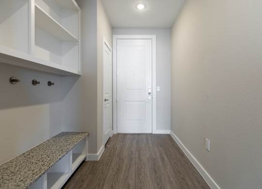 A hallway with a bench and a door.