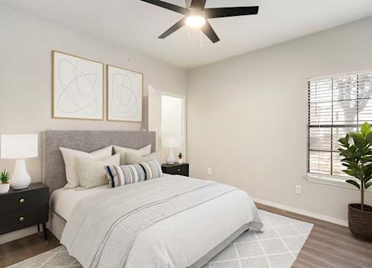 A bedroom with a large bed, a ceiling fan, and two wall lamps.