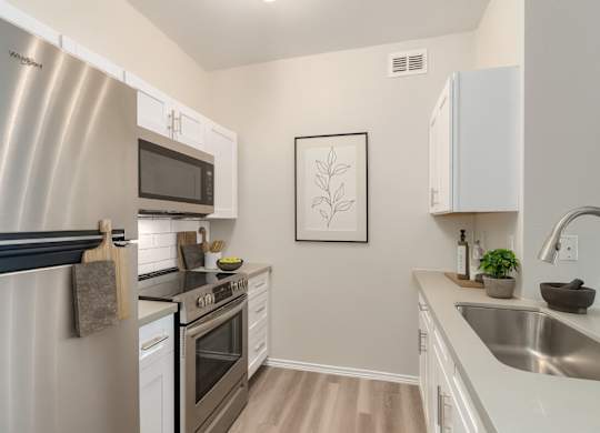 A modern kitchen with a stainless steel refrigerator and white cabinets.