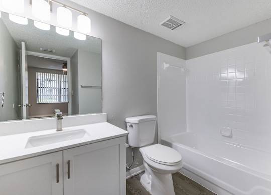 A white bathroom with a toilet, sink, and bathtub.