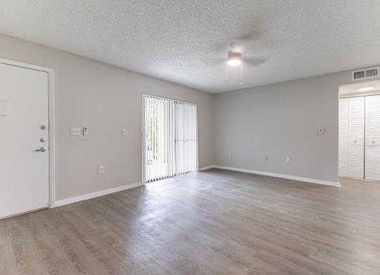 A spacious room with a sliding glass door and a ceiling fan.