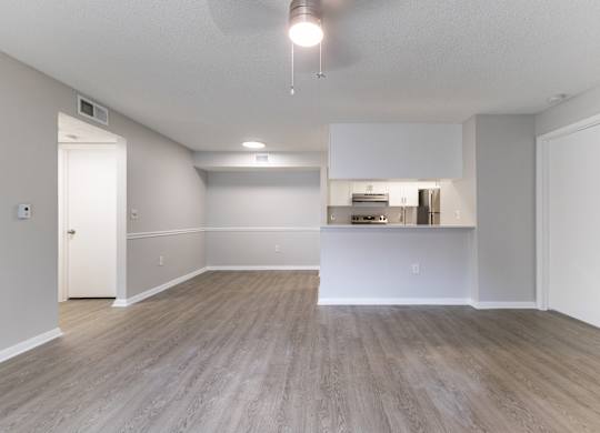 A spacious room with a kitchenette in the background.