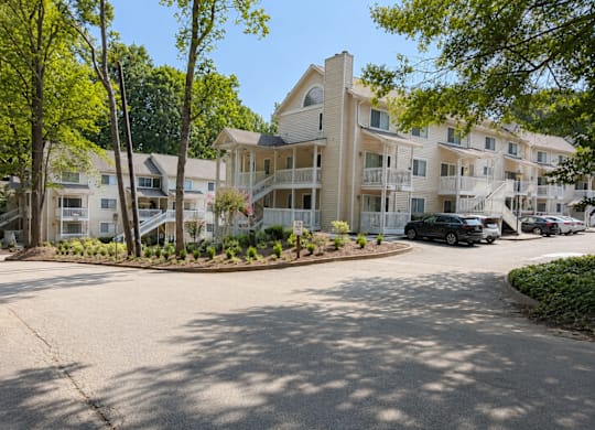 A sunny day at a residential complex with a black car parked in the driveway.
