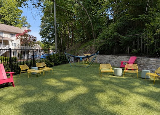 A backyard with a hammock, lawn chairs, and a trampoline.