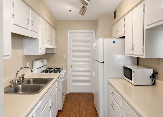 A small kitchen with white cabinets and appliances.