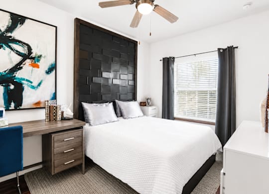 A bedroom with a bed, desk, and chair.