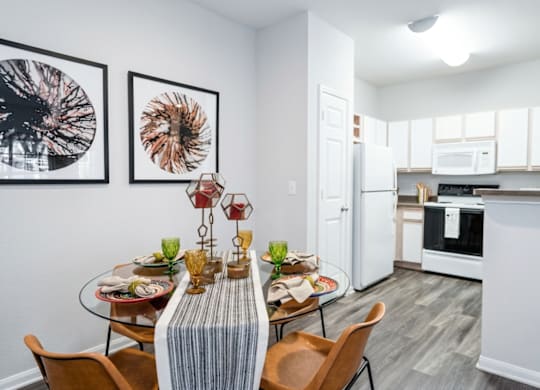 A modern kitchen with a dining table set for two.