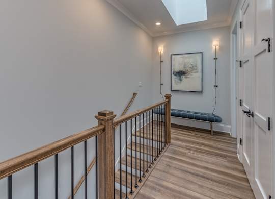 A modern builder grade upstairs hallway with a skylight.