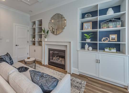 A modern builder grade living room with a fireplace surrounded by custom build ins and white couch.