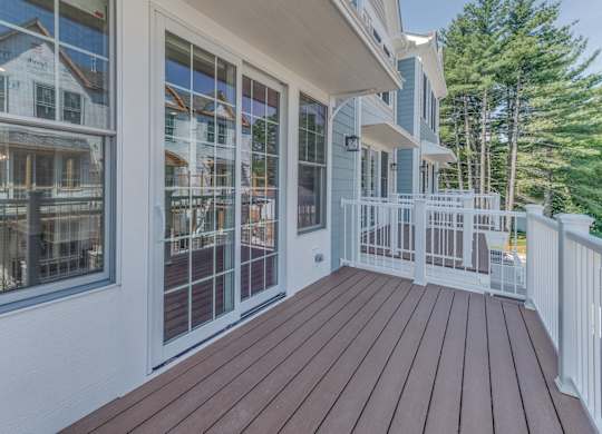 A wooden deck with a white railing with a sliding door right off the kitchen/dining room.