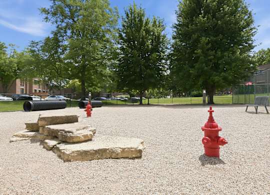A red fire hydrant stands in the middle of a gravel area.