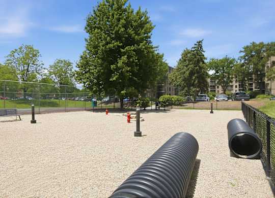 A playground with a large black tube in the foreground.