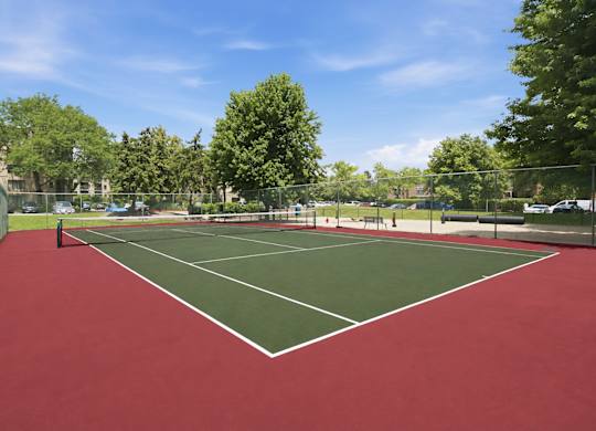 A tennis court with a red surface and white lines.