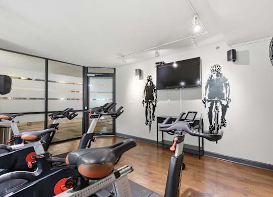 A room with exercise bikes and a television mounted on the wall.