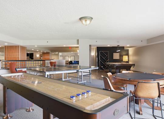 A billiard table is in the middle of a room with chairs and a bar.