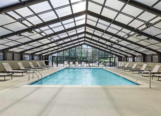 A large indoor swimming pool with sunroof and lounge chairs.