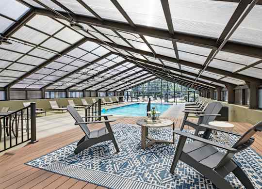 A sunroom with a pool and lounge chairs.