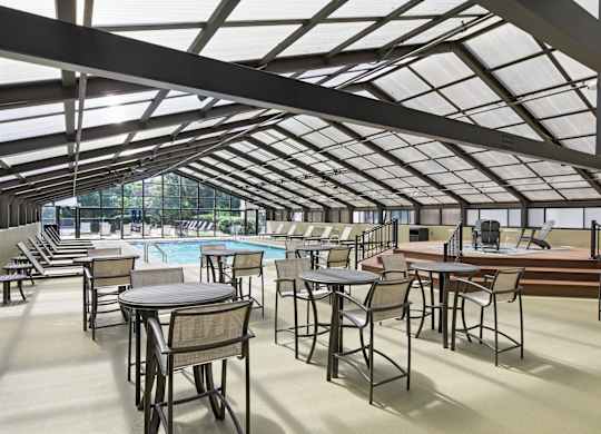 A large room with tables and chairs and a pool table.
