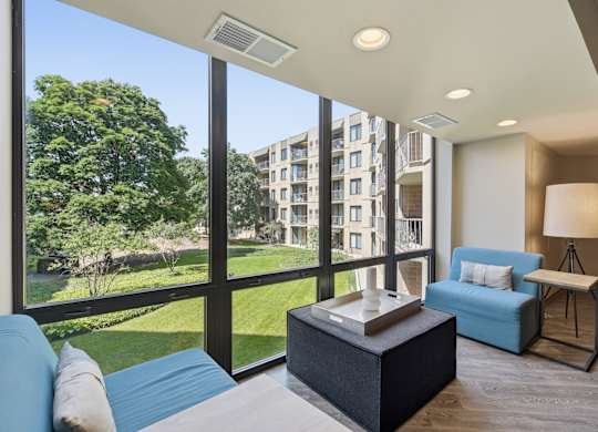A modern living room with a view of a green lawn and trees.