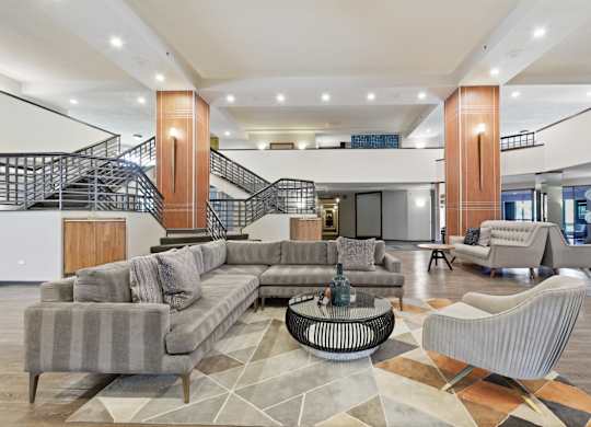 A living room with a spiral staircase and a grey sofa.