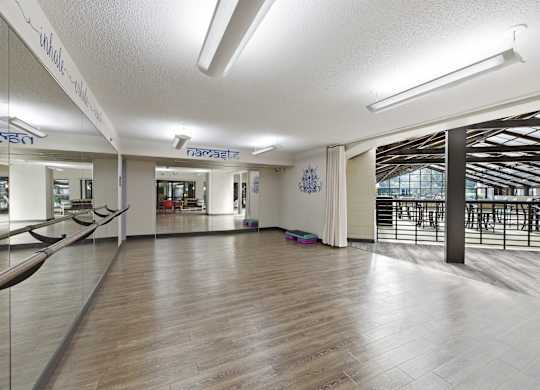A spacious room with wooden floors and a large mirror on the wall.