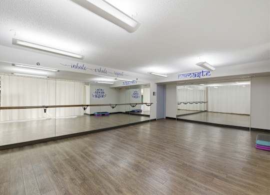 A dance studio with mirrors on the wall and wooden flooring.