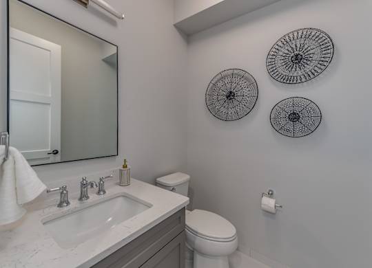 A modern builder grade powder room on the first floor with a sink, mirror, and toilet.
